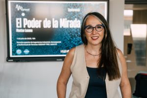 Montse Lucena delante del cartel que anuncia la conferencia El Poder de la Mirada.